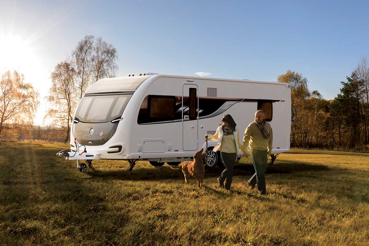 a couple and their dog enjoying mobile living in a field