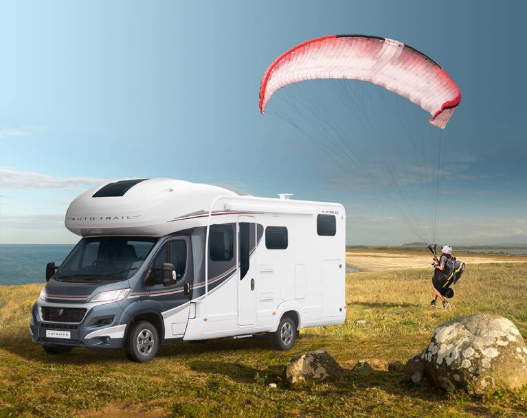A man paragliding over his motorhome