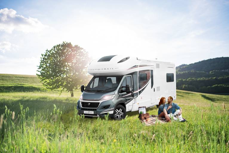 family sat next to a motorhome in field